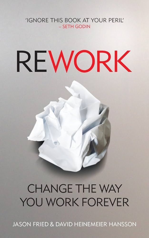 Cover of the book Rework with a crumpled paper in the center. The title REWORK is written in bold, with RE in black and WORK in red. The subtitle is Change the Way You Work Forever by Jason Fried & David Heinemeier Hansson.
